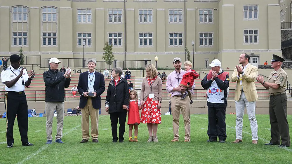 group of people gathered on football field, clapping