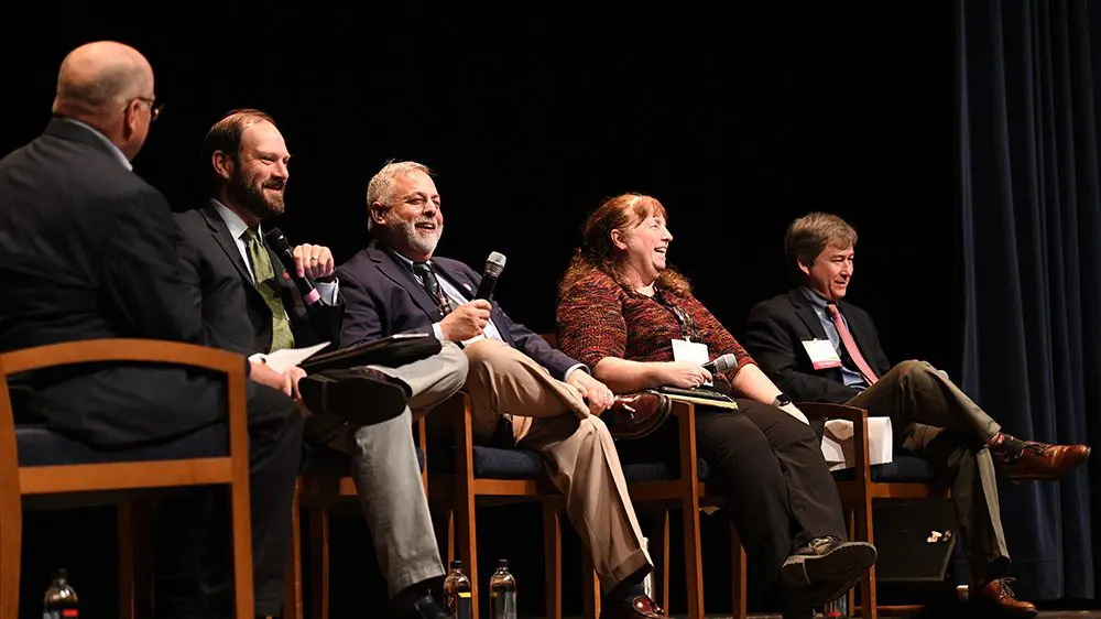 panel of individuals seated on stage speaking