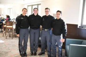 four cadets standing in a row, smiling