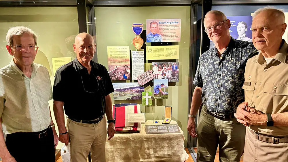 men smiling, standing in front of Kearfott exhibit in VMI Museum