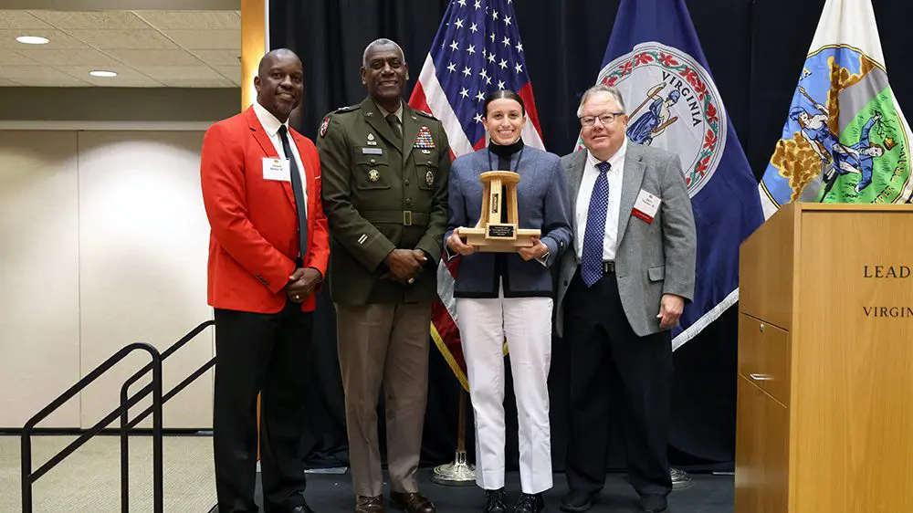 cadet poses with three-legged stool award and smiles with athletic director, superintendent, and Keydet Club president