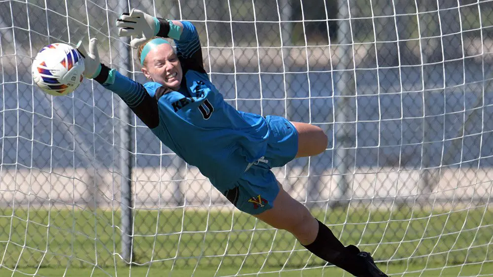 female soccer goalee leaping to block a goal
