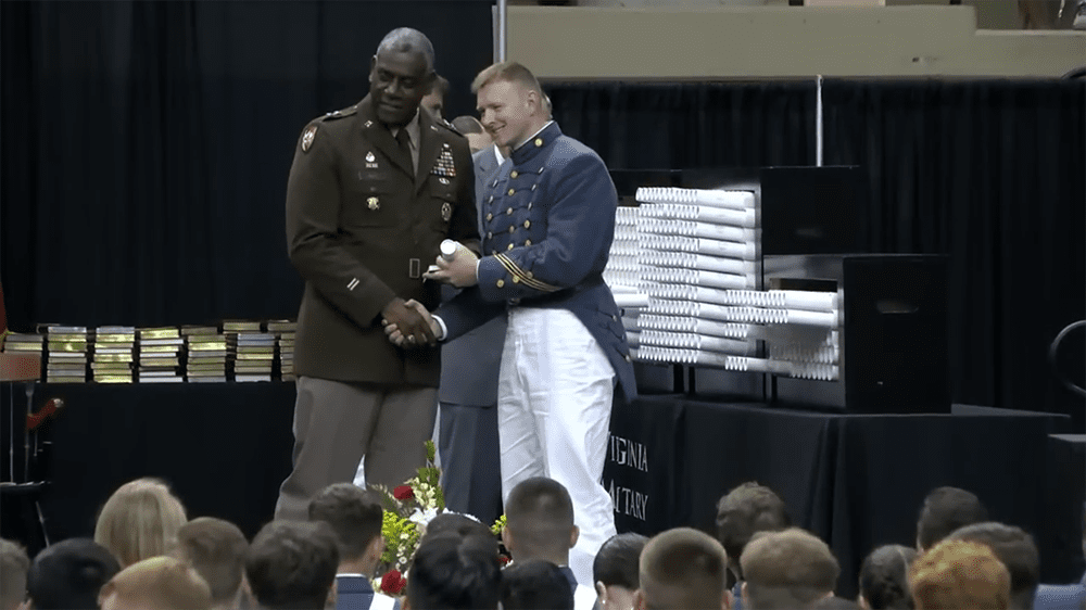 cadet receiving diploma from Maj. Gen. Wins, shaking hands and smiling