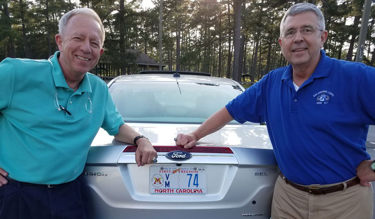 chapter alumni standing beside vmi license plate