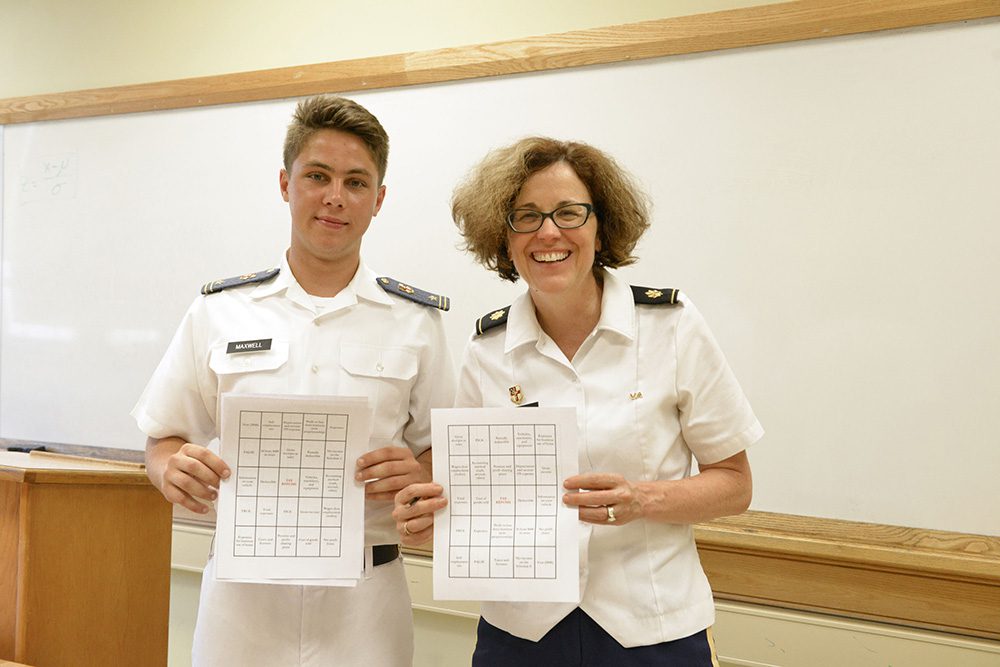 cadet and professor smile, posing with bingo cards