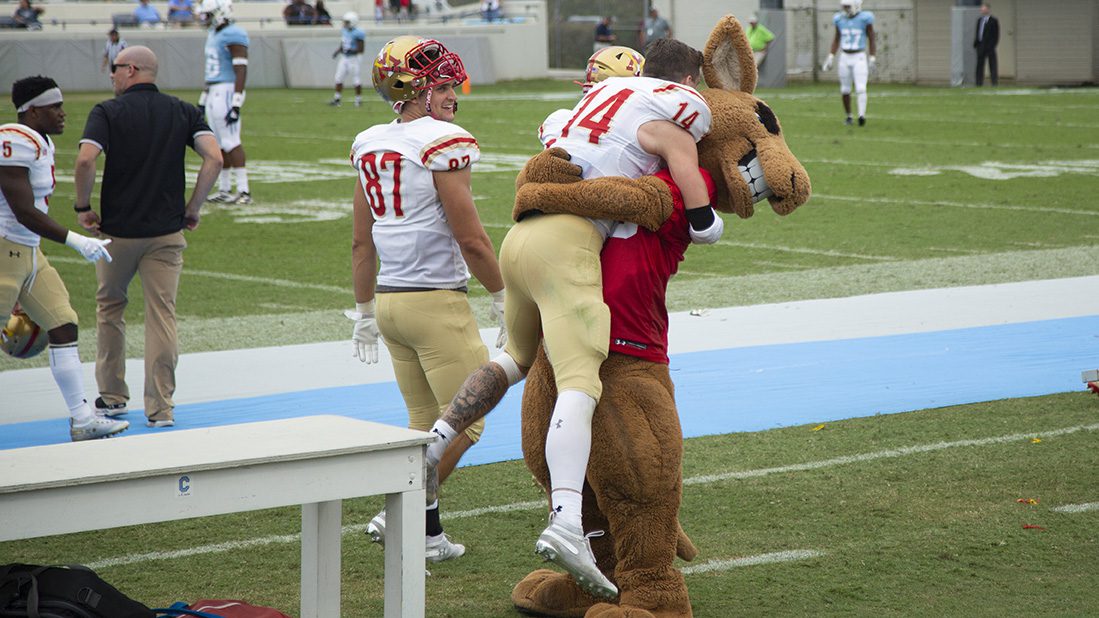 Moe mascot hugging and lifting a VMI football player