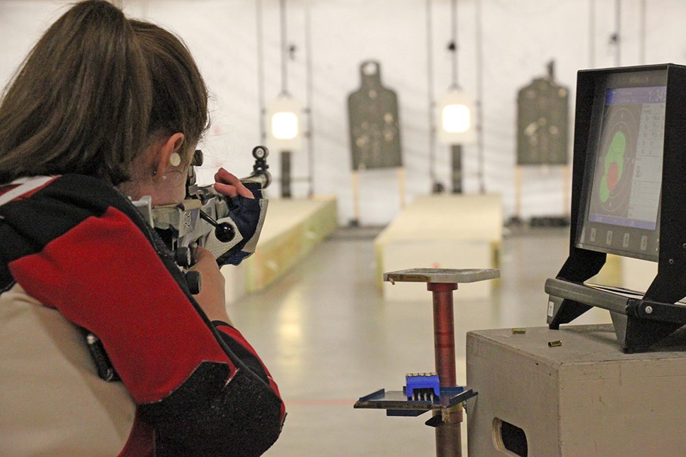 female rifle team member aiming her rifle at target