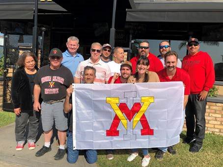 Group of people holding VMI flag, smiling.