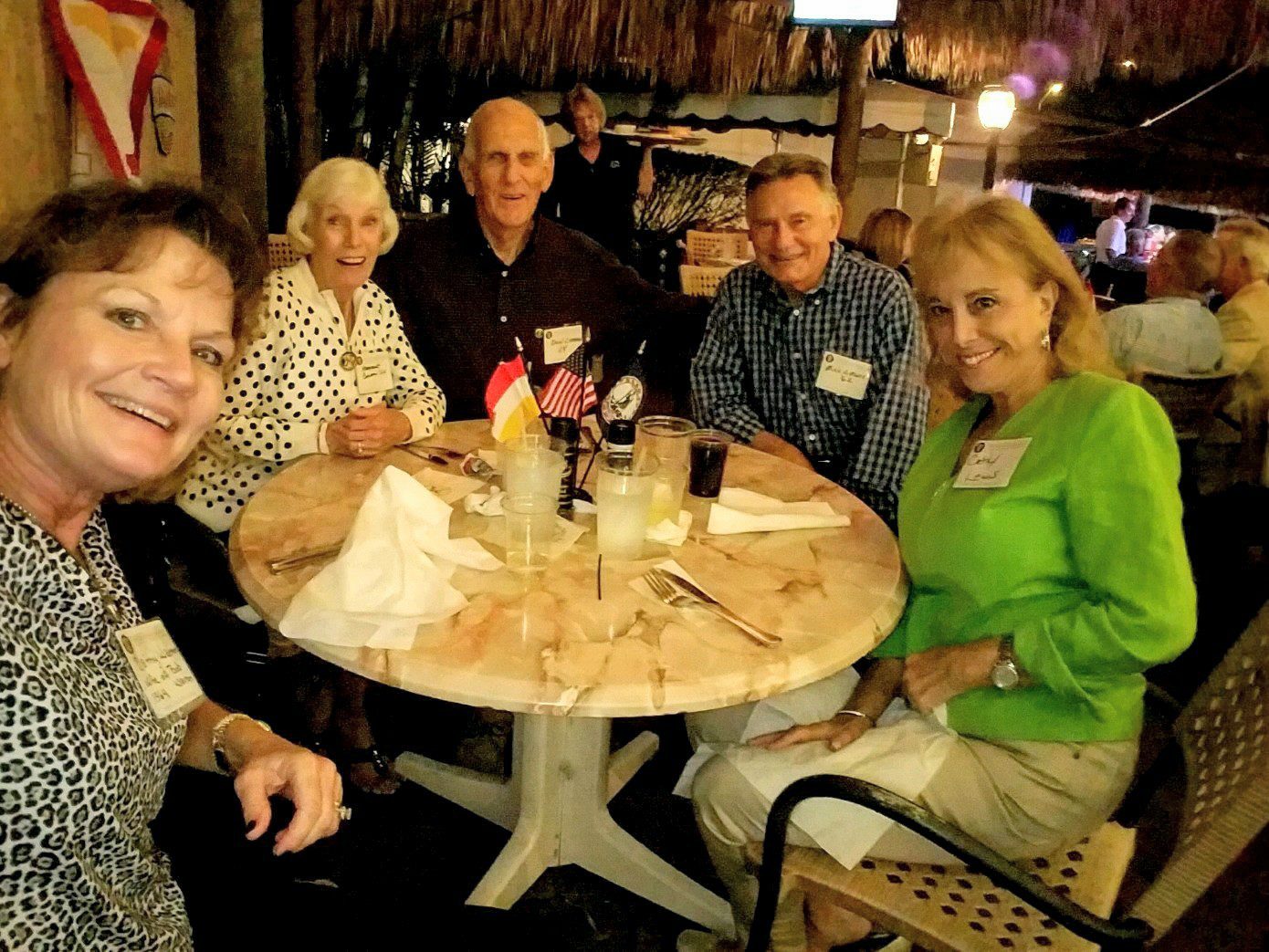 Group of men and women seated at table together, smiling.