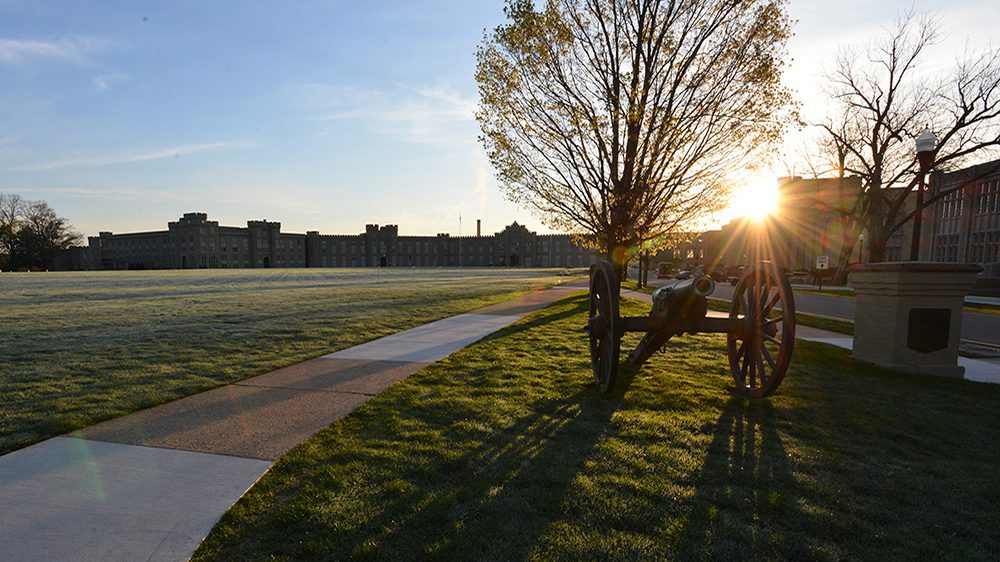 cannon and tree with barracks in the background