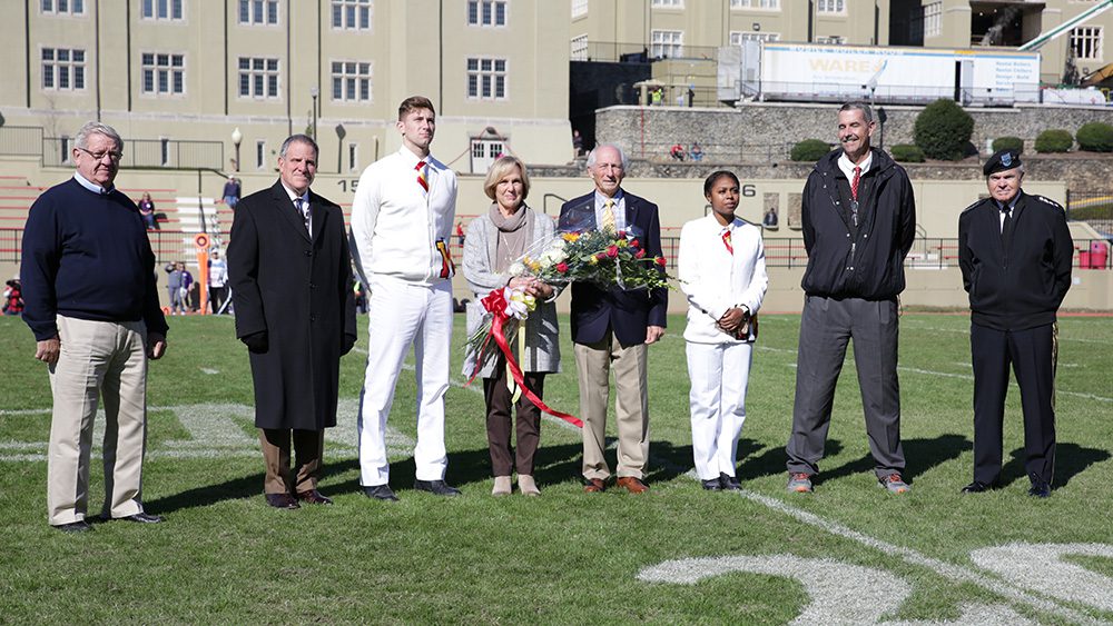 Lois Ford-Bouis receiving the Spirit of VMI Award standing on football field with Gen. Peay and members of the VMI community.