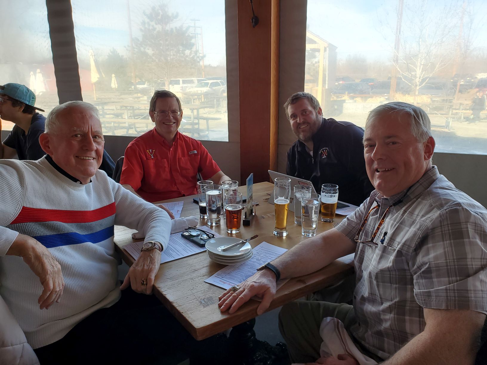 Four men seated around dining table, smiling.