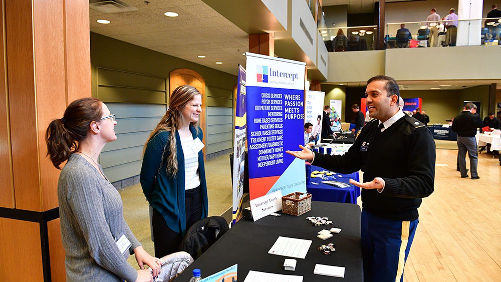 man and two women interacting with each other at career fair