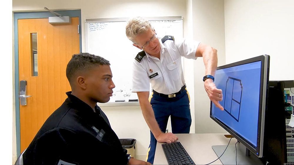 professor pointing to computer screen and talking to cadet