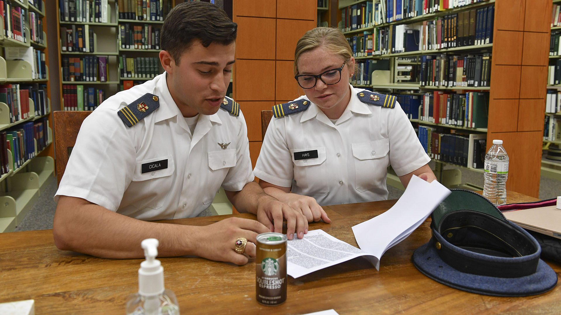 two cadets seated at table looking at papers