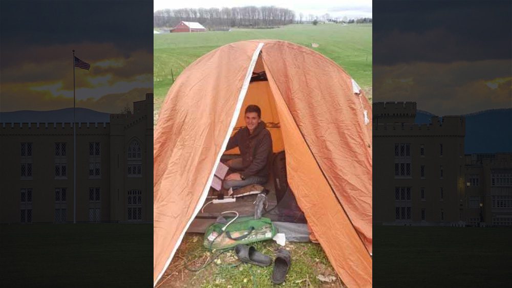 cadet in a tent outdoors with laptop and notebooks