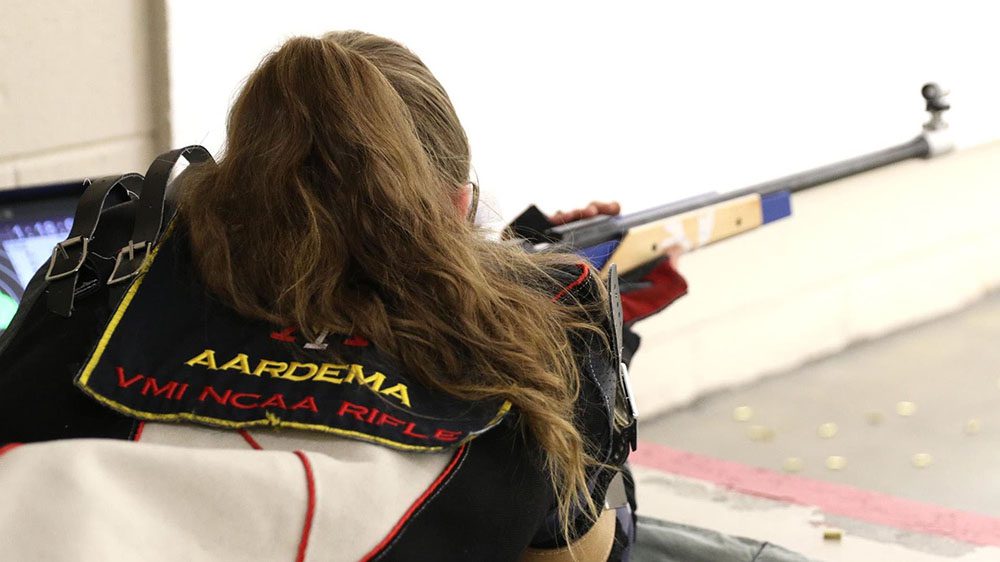 Rifle team member aiming rifle at target.