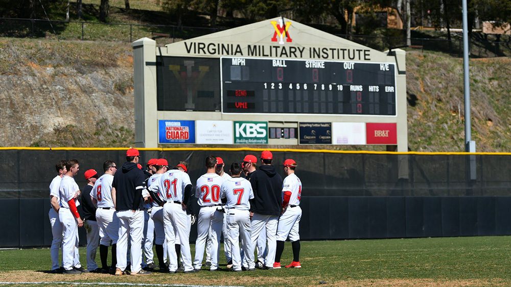 baseball players gathered on field with scoreboard in background