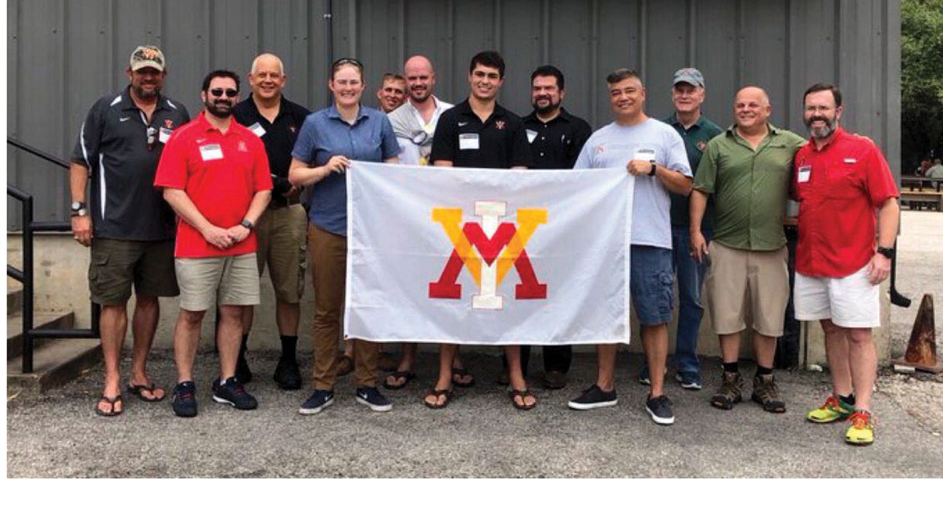 Group of people holding a VMI flag and smiling.