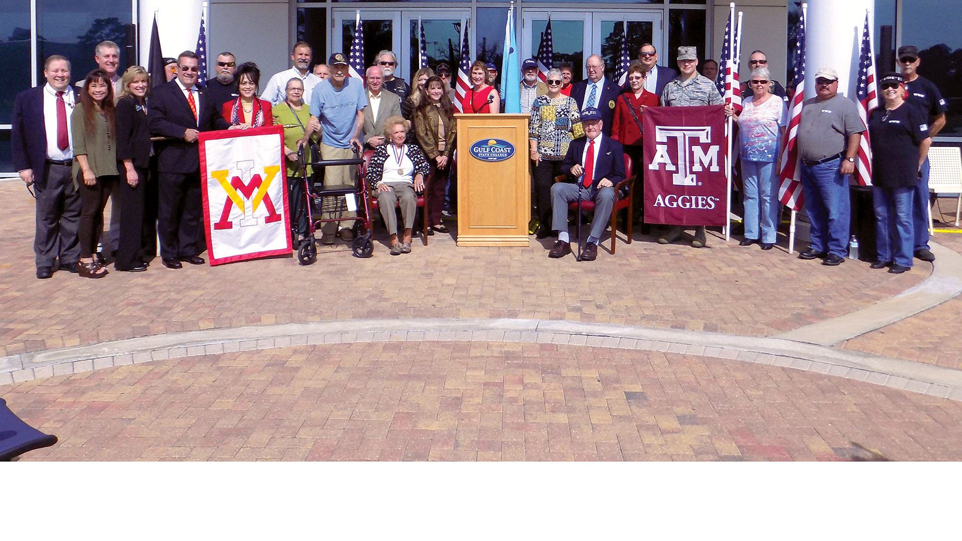 group of people smiling, holding VMI and Texas A&M flags