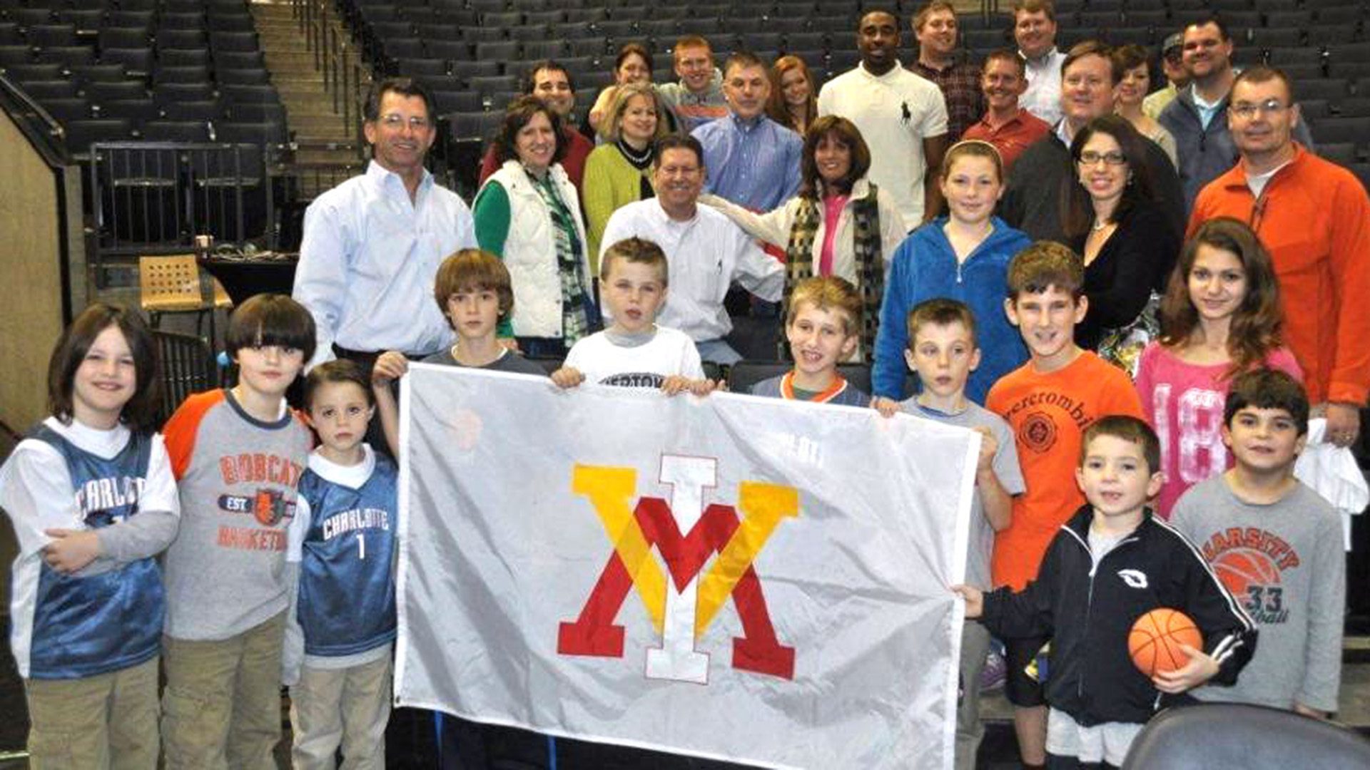 group of children and adults holding VMI flag