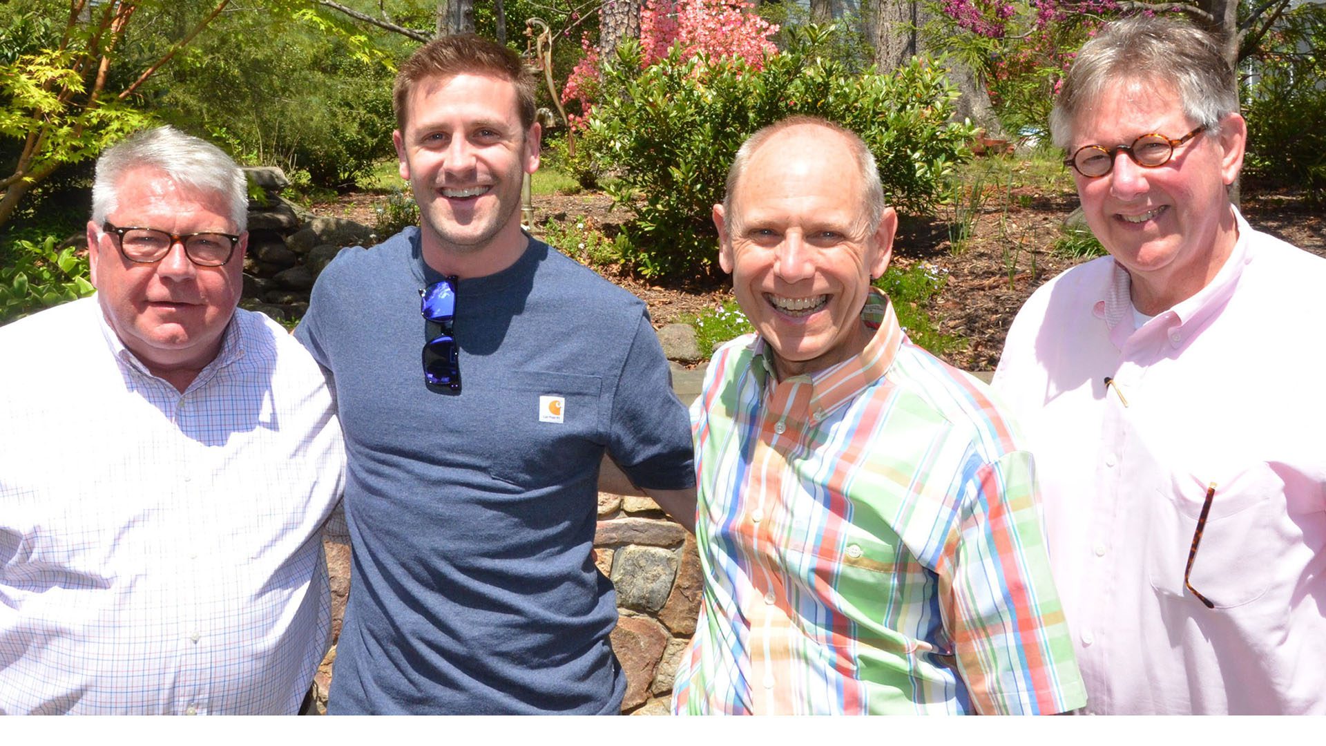 Four men pose together, smiling.