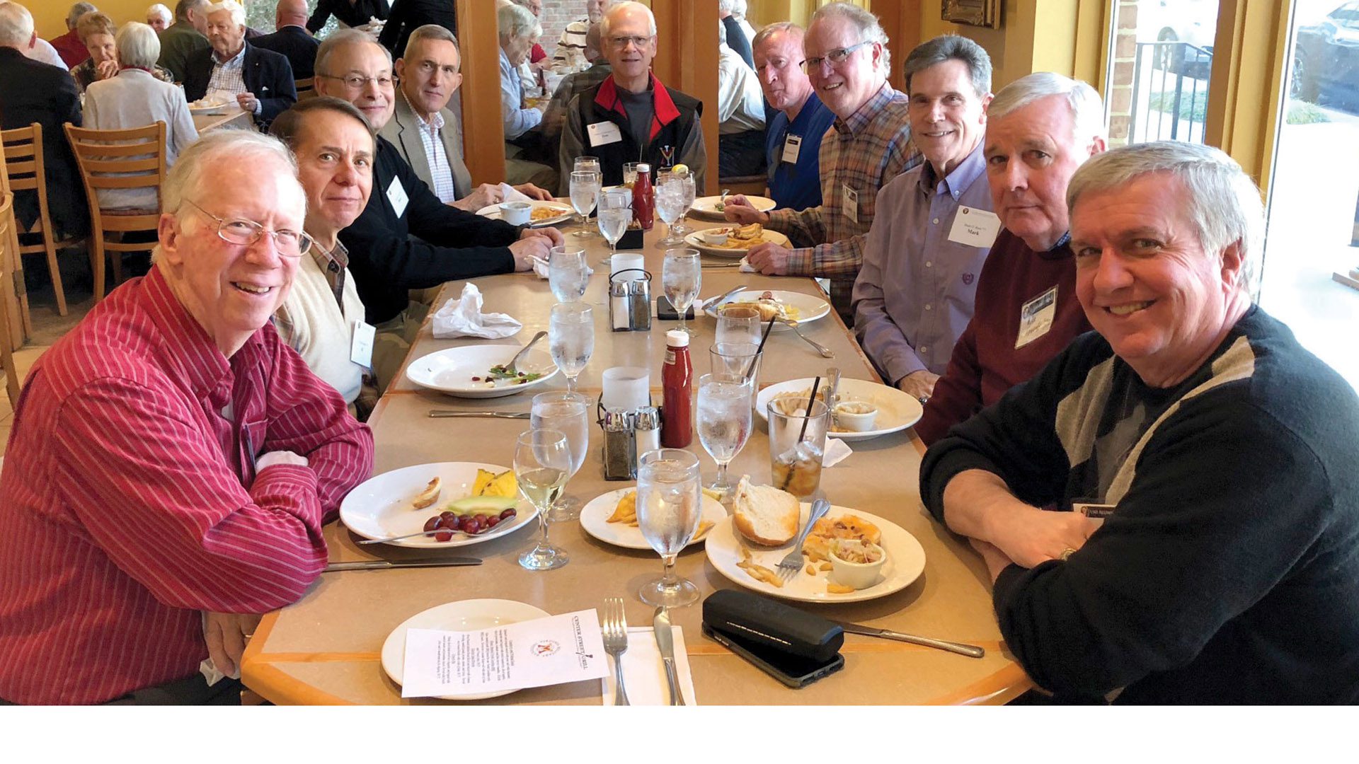 Group of men sitting around a table smiling.