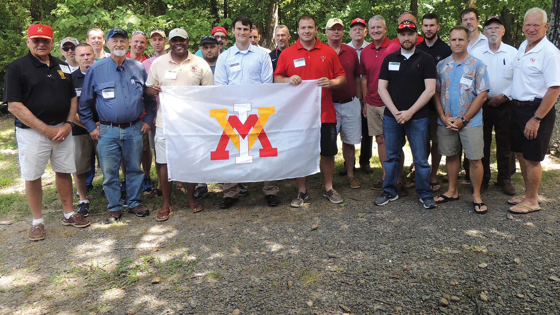 Group of people holding up a VMI flag, smiling.