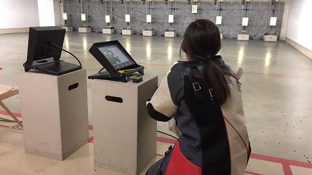 Rifle team member aiming rifle at target.