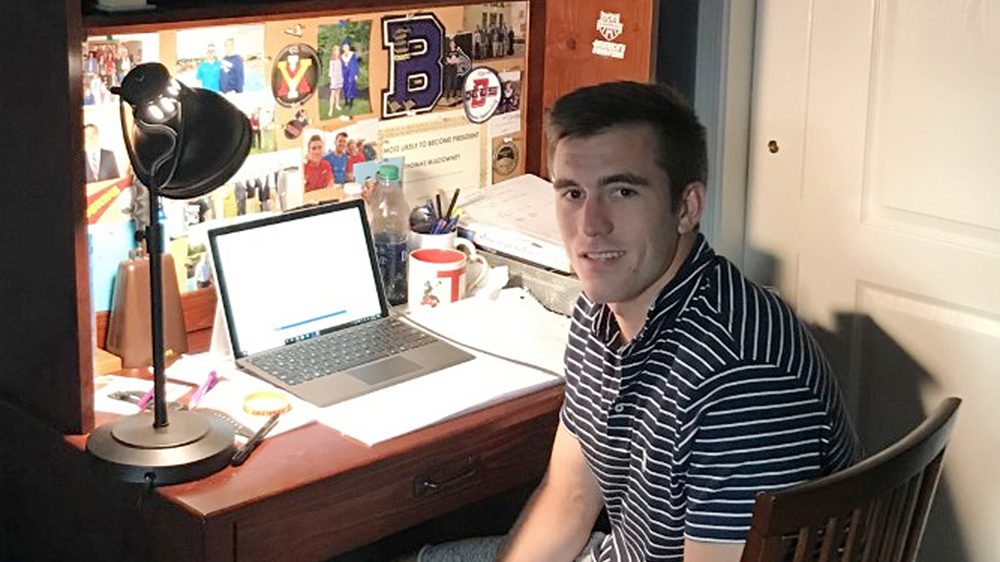 man sitting at desk with laptop open, smiling