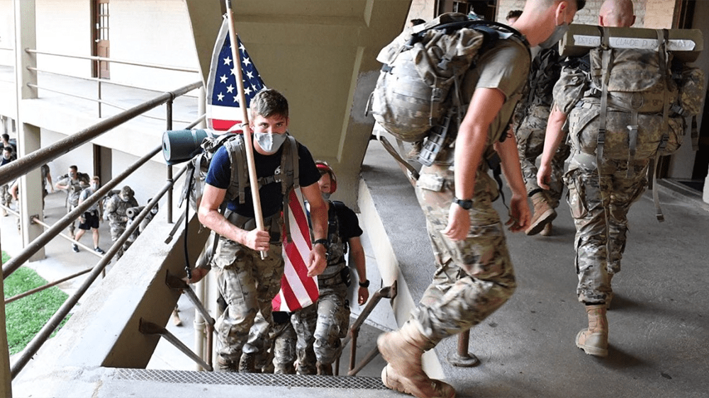 cadets climbing stairs, one holding American flag