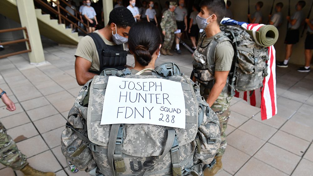 cadet wearing backpack with sign that says 