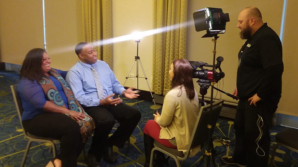 man and women seated across from another woman and man, being interviewed on camera.