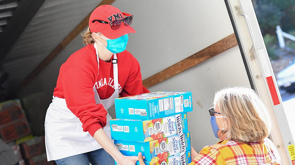 Woman handing multiple boxes of food to another woman