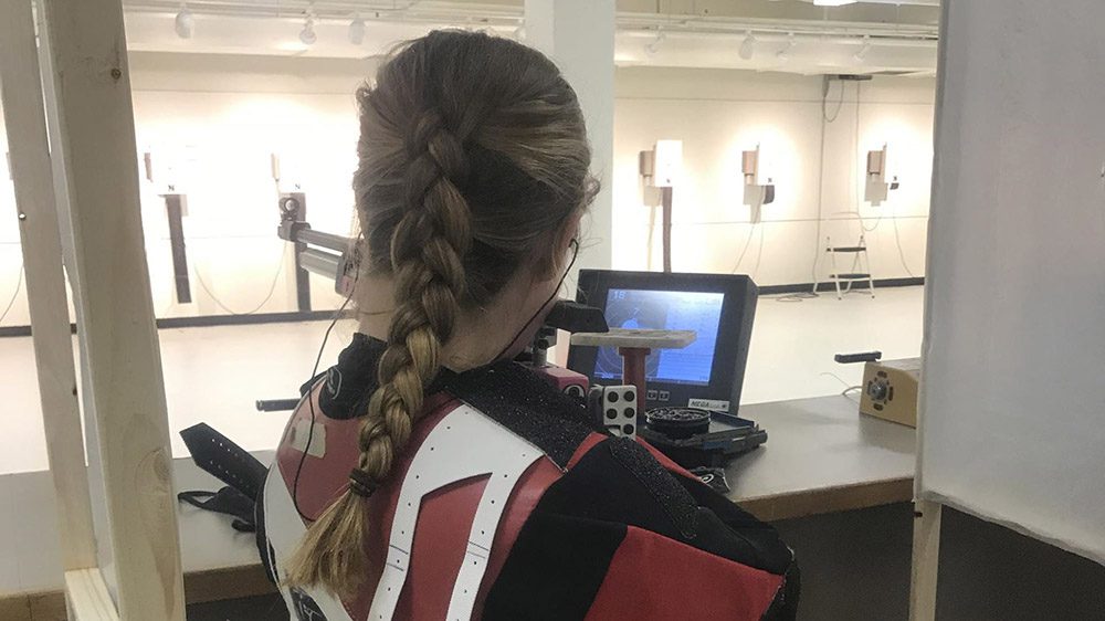 Rifle team member aiming rifle at target.