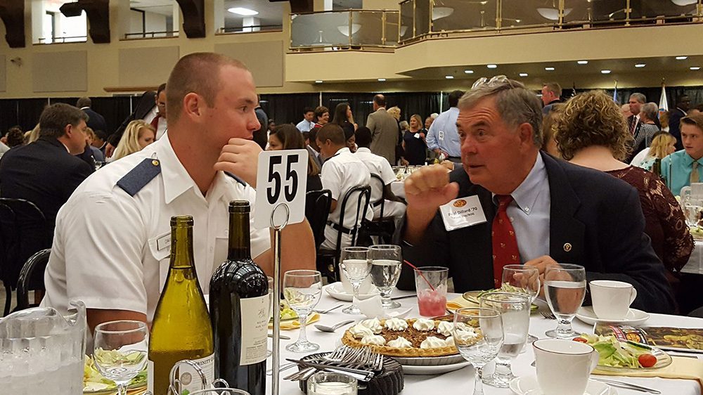 Man seated at table conversing with a cacdet