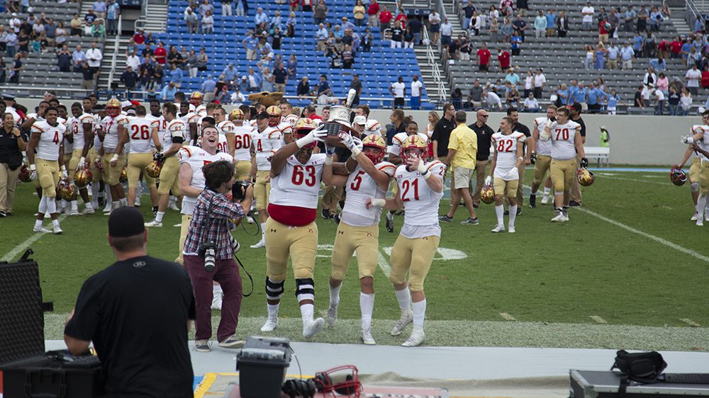 football players hoisting Silver Shako trophy