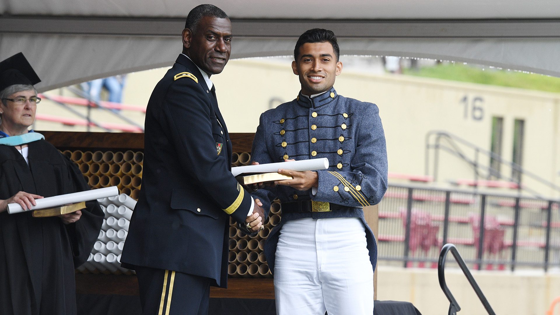 cadet shaking hands with Maj. Gen. Wins, smiling and receiving diploma
