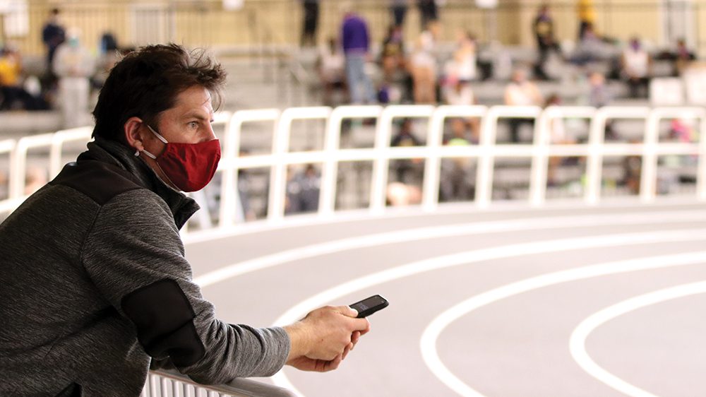 Coach Ludtke watching from side of indoor track.