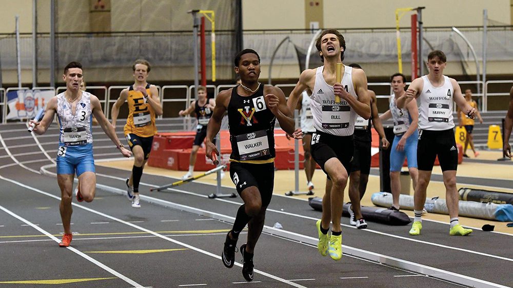 Track athletes running race on indoor track.