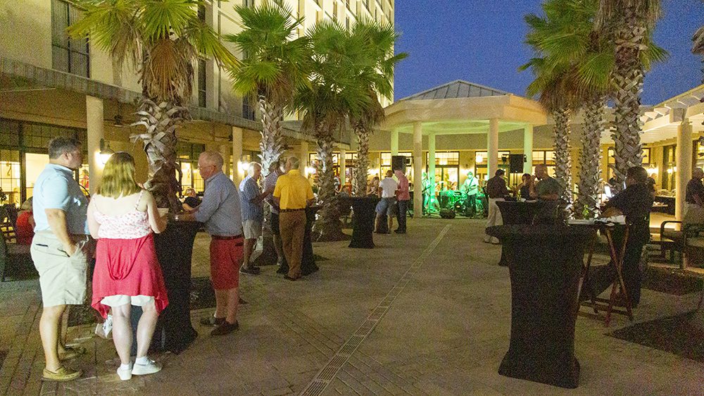 people standing in courtyard at high-top cocktail tables.