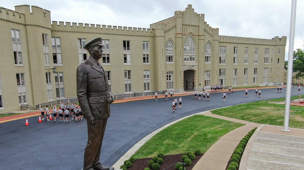old barracks with Marshall statue in the foreground, and cadets walking in the background