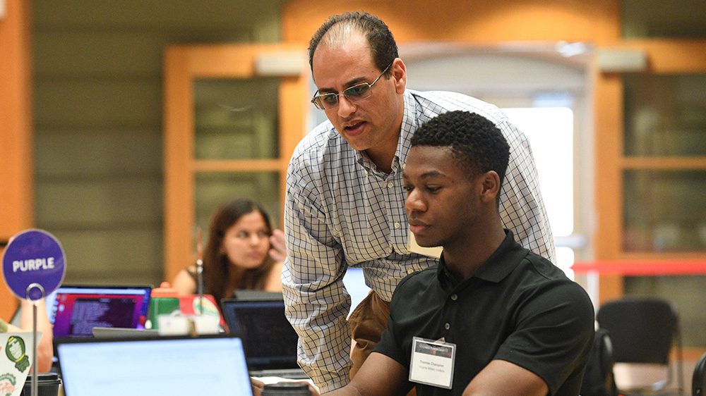 student working on computer and instructor looking over their shoulder