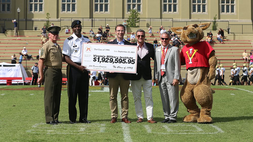 Men posing with Moe, holding check from Class of 1995