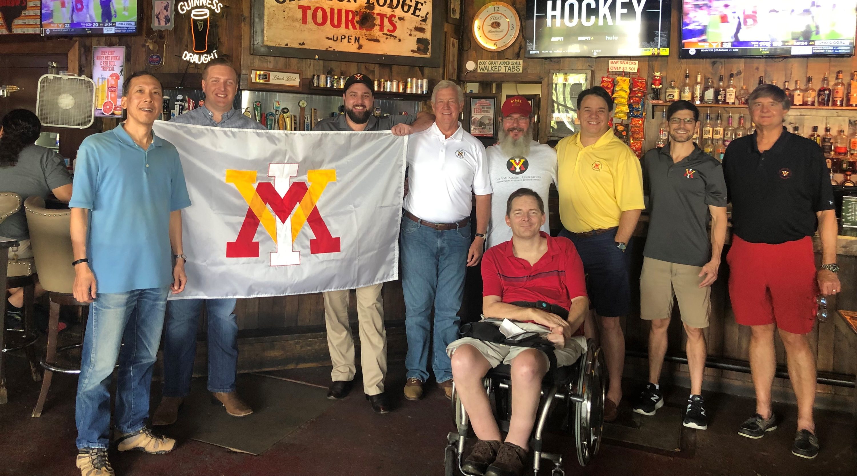 group of people holding up a VMI flag and smiling