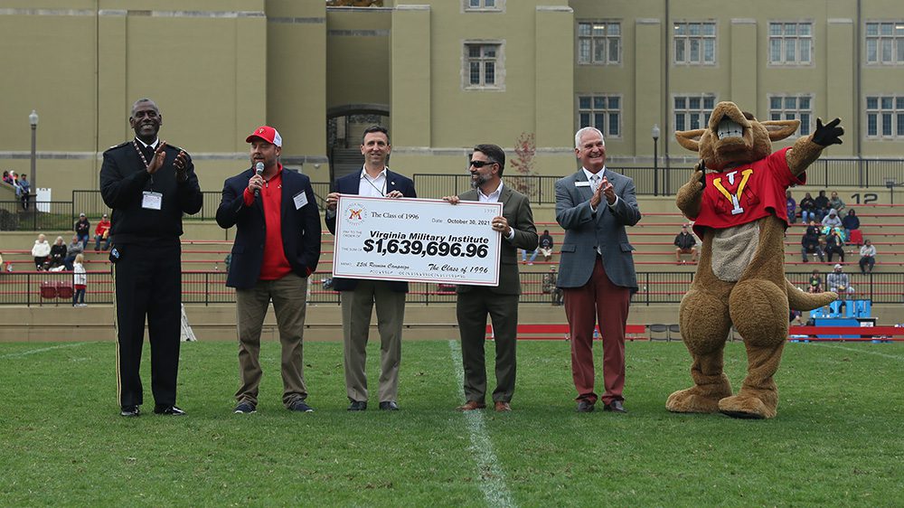 two men hold up giant check to the Institute from the Class of 1996 while others cheer