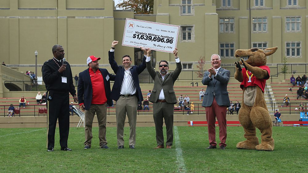 two men hold up giant check to the Institute from the Class of 1996 while others cheer