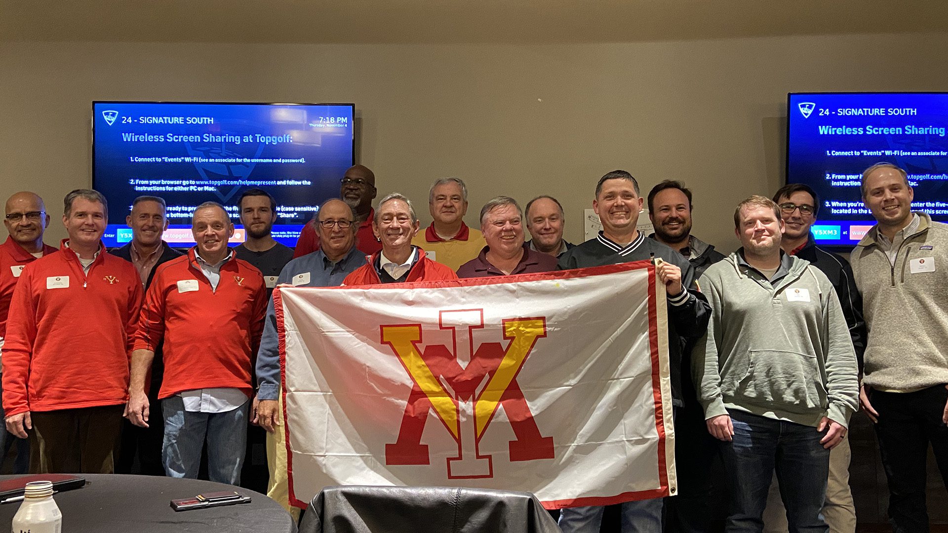 Large group of people holding up a VMI flag and smiling.