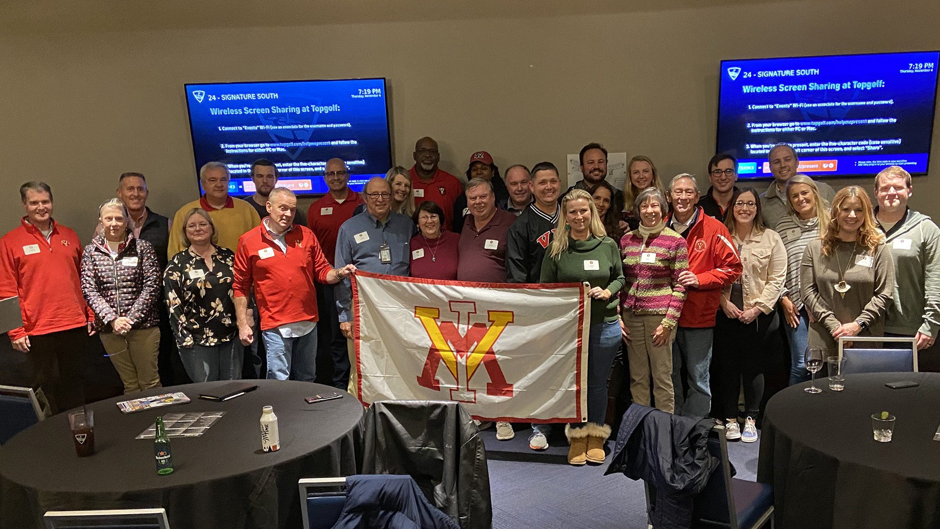 Large group of people holding up a VMI flag and smiling.