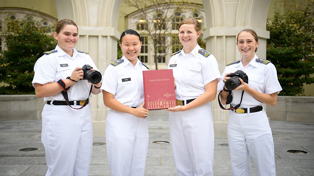 yearbook staff holds Bomb and cameras, smiling